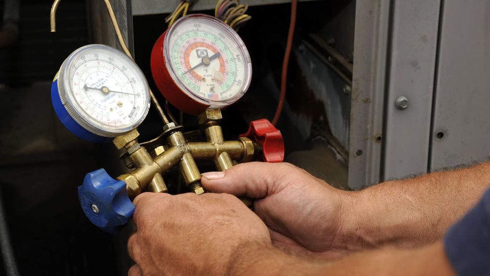 HVAC repair man holding blue cold and red hot temperature gauges